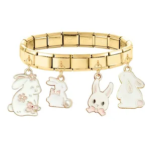 Detailed macro view of gold stainless steel charm bracelet with white bunny pendants