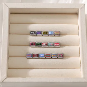 Macro shot of 16 colorful enamel stainless steel charms with various mood quotes in a tray