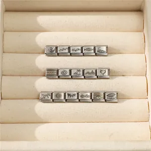Macro detail of Italian charms with laser-etched nature patterns in stainless steel