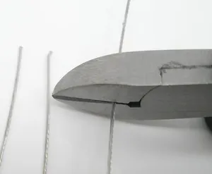 Macro shot of industrial steel wire rope being cut by heavy duty diagonal pliers