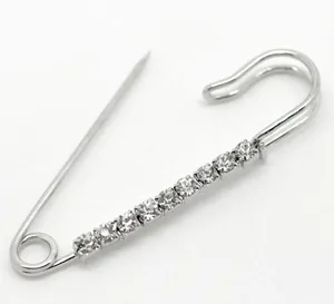 Close-up of silver safety pin brooch featuring nine sparkling white rhinestones on metal