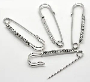 Detailed view of four silver-colored safety pins set with sparkling round rhinestones