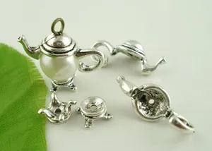Macro view of disassembled antique silver teapot pendant parts with a white pearl bead