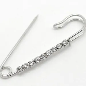 Vintage safety pin brooch with nine inlaid rhinestones on a polished silver finish