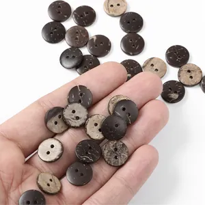 Close-up of hand holding natural coconut wood buttons with unique grain and dual holes
