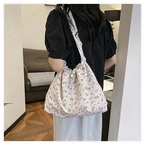 Détail d'un sac bandoulière à fleurs avec cordon de serrage et large sangle réglable