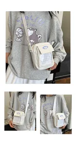Detail of white canvas crossbody bag featuring a transparent mesh pocket and fashion label