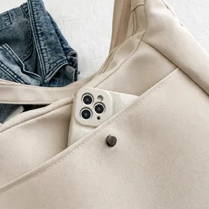 Détail d'une poche latérale portable sur un cabas en toile montrant le rangement du mobile