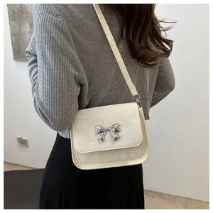 Detail of off-white crossbody bag featuring a pleated texture and silver metal butterfly