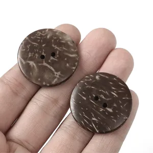 Detailed macro view of two-hole brown coconut texture buttons held to show size scale