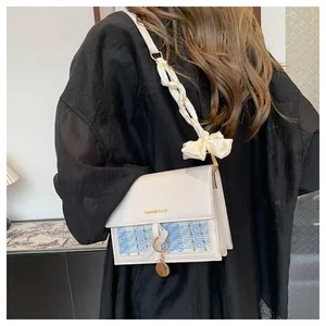 Detail of plaid patchwork bag with silk scarf wrapped chain strap and bow on model