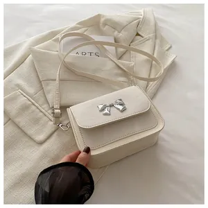 Detailed view of cream-colored crossbody bag featuring a 3D silver butterfly bow ornament
