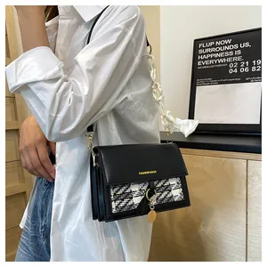 Detail of a black crossbody bag with silk scarf decoration and metallic fashion clasp