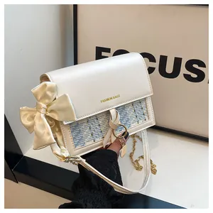 Detail of white leather small square bag with tweed flap and satin bow accent