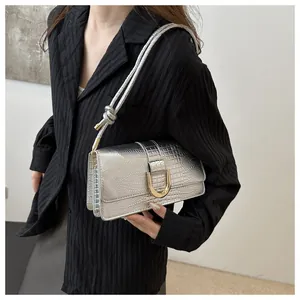 Détail du sac à bandoulière argenté à motif crocodile avec boucle dorée et bandoulière à nœud