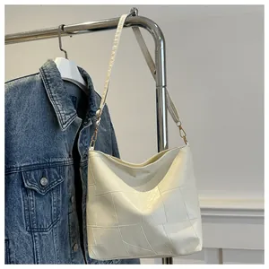 Detail der cremeweißen Hobo-Tasche mit geometrischem Patchwork und goldenen Haken