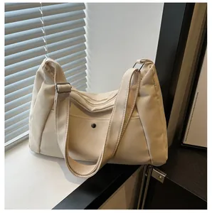 Détail du sac fourre-tout en toile crème montrant la poche extérieure et la fermeture éclair