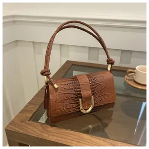 Détail du sac à main marron texture crocodile avec boucle métallique dorée en forme de U