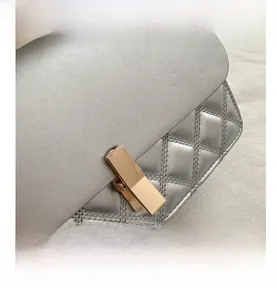 Détail de sac à main argenté matelassé avec une boucle de verrouillage dorée élégante