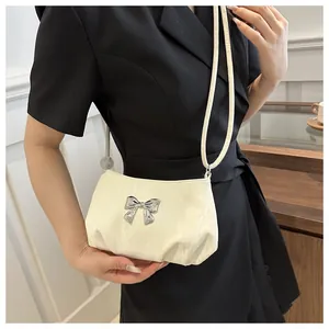Detail of cream pleated shoulder bag with a polished silver butterfly metal buckle