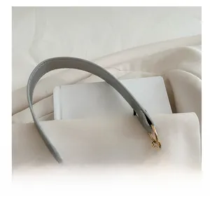 Détail de bandoulière en cuir gris avec chaîne dorée et connecteur circulaire