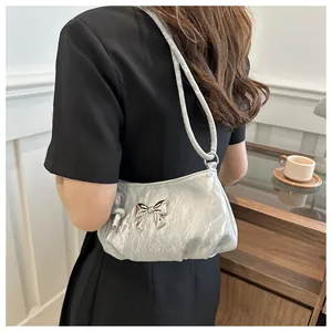 Chic silver pleated shoulder bag with metal butterfly buckle shown on model