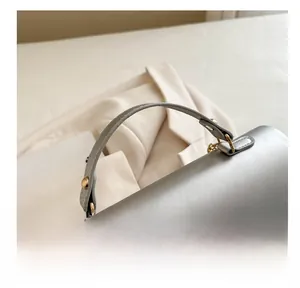 Détail de la poignée confortable avec anneaux en D et rivets en métal doré sur le sac argenté