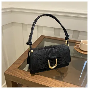 Détail du sac noir à motif crocodile avec une boucle dorée en forme de U élégante