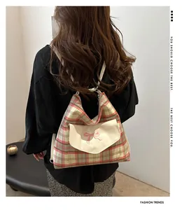 Detail of checkered tote bag with a pink bow embroidery and front flap pocket on a model