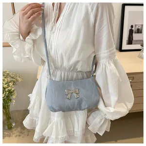 Detail of light blue crossbody bag with silver butterfly buckle and textured fabric
