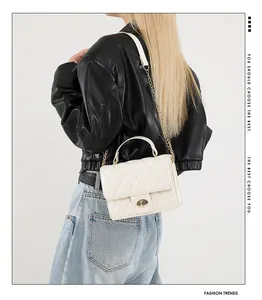 Detail of white quilted crossbody bag with golden chain strap and twist-lock clasp