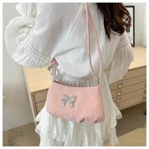 Detail of pink shoulder bag featuring a silver butterfly buckle and white pearl strap accents