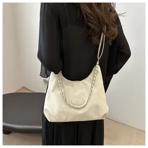 Close-up of white ruched hobo bag with metal chain detail and half-moon silhouette