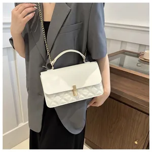 Détail du sac bandoulière blanc matelassé avec chaîne dorée et fermoir sur un modèle
