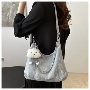 Detailed view of light gray pleated hobo bag with cloud pendant on model's shoulder