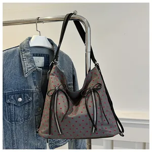 Detail der grauen Denim-Tasche mit roten Herzmustern und schwarzen Bandschleifen