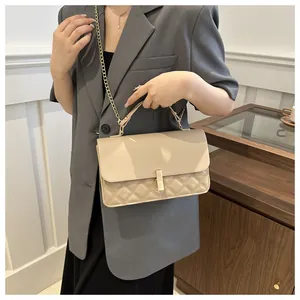Détail du sac beige matelassé avec fermoir rectangulaire doré et bandoulière chaîne