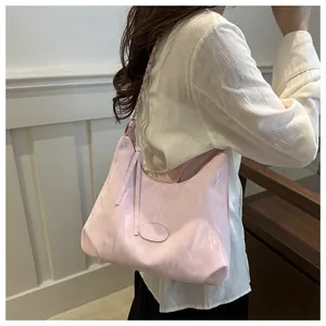 Detail of pink hobo bag with pleated texture and silver chain strap on shoulder