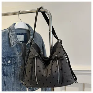 Detail der grauen Denim-Hobo-Tasche mit schwarzen Punkten, Schleifenstickerei und Reißverschluss