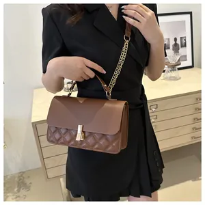 Détail d'un sac en cuir marron matelassé avec fermoir doré et bandoulière sur un mannequin