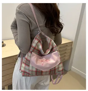 Detail showing the pink bow embroidery and plaid canvas texture of the tote bag