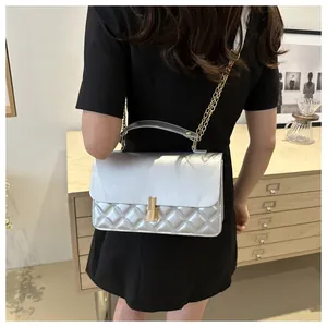Détail du sac argenté matelassé avec chaîne dorée porté par un mannequin en robe noire