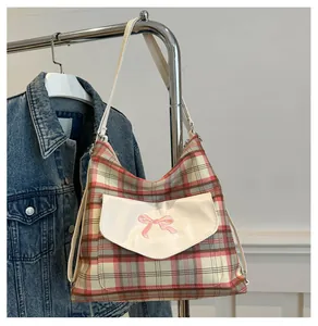 Detail of checkered tote bag with pink satin bow and leather strap on a metal hanger