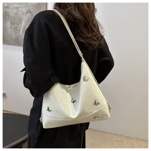Detailed view of silver butterfly metal buckles on white textured faux leather hobo bag