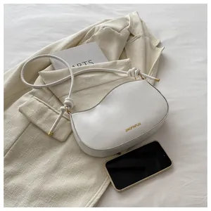 Top-down shot of a white bow shoulder bag with fine leather texture on a beige suit