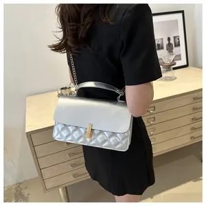 Détail du sac à bandoulière argenté matelassé avec fermoir doré et chaîne sur modèle