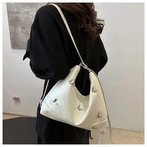 Detail of cream white half-moon shoulder bag with silver butterfly hardware accents