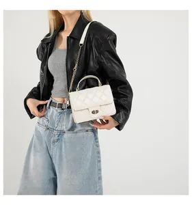 Detail of white quilted crossbody bag featuring golden twist lock and chain strap