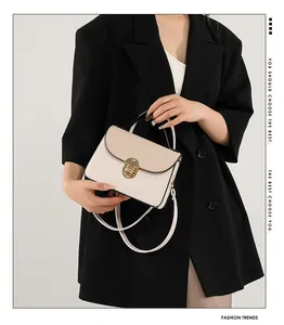 Dettaglio della borsa beige a contrasto con chiusura dorata su blazer nero elegante