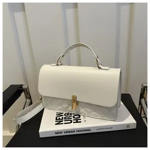 Gros plan du sac à main matelassé blanc avec fermoir tournant doré et rabat en cuir